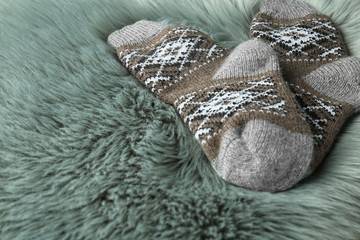 Knitted socks on grey faux fur, closeup. Space for text