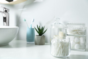 Fototapeta na wymiar Jar with cotton swabs on white countertop in bathroom