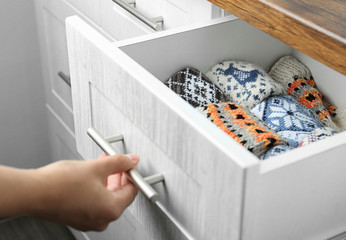 Woman opening drawer with warm socks indoors, closeup