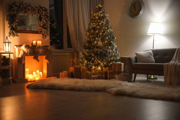 Stylish interior with beautiful Christmas tree and decorative fireplace at night
