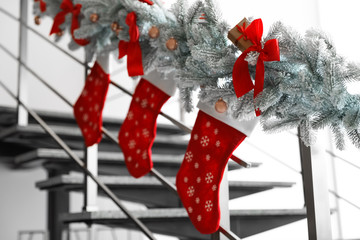 Santa stockings and garland on railing indoors. Christmas decor idea