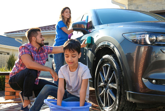 Happy Family Washing Car At Backyard On Sunny Day