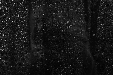 Glass with rain drops against dark background