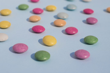 Blue background with multi-colored dragees scattered on the surf