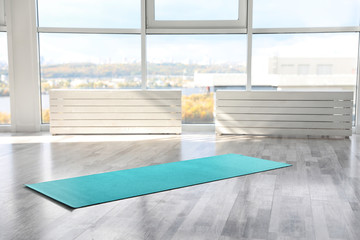 Unrolled light blue yoga mat on floor in room