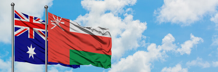 Naklejka premium Australia and Oman flag waving in the wind against white cloudy blue sky together. Diplomacy concept, international relations.