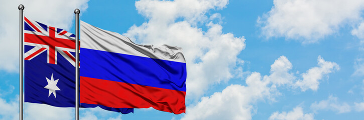 Fototapeta premium Australia and Russia flag waving in the wind against white cloudy blue sky together. Diplomacy concept, international relations.