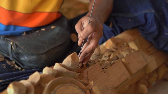 Closeup shot of a master craftsman doing traditional wood carving