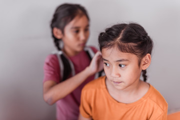 Asian elder sister are making braids for her young sister.