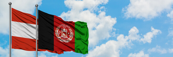 Austria and Afghanistan flag waving in the wind against white cloudy blue sky together. Diplomacy...