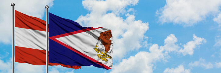 Austria and American Samoa flag waving in the wind against white cloudy blue sky together....