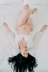 upside down view of gorgeous asian chinese pregnant woman at home in sexy lingerie and robe lying...