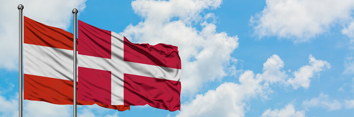 Fototapeta premium Austria and Denmark flag waving in the wind against white cloudy blue sky together. Diplomacy concept, international relations.