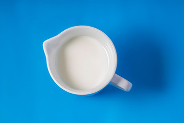 Porcelain White Creamer Dispenser Pitcher with cream on a blue background