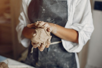 Woman in a pottery. Master make a dishes. Artist works with a clay - obrazy, fototapety, plakaty