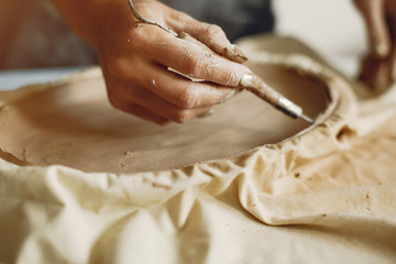 Woman in a pottery. Master make a dishes. Artist works with a clay