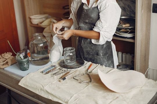 Woman in a pottery. Master make a dishes. Artist works with a clay