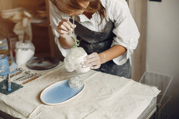 Woman in a pottery. Master make a dishes. Artist works with a clay