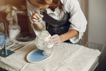 Woman in a pottery. Master make a dishes. Artist works with a clay