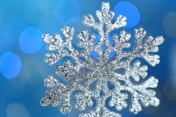 Winter holidays . Christmas and New Year. Winter season.Silvery snowflake close-up on a bright blue background with blue bokeh.