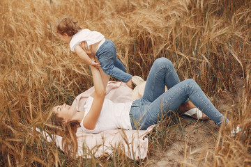 Naklejka na ściany i meble Family in a summer field. Mother in a white t-shirt. Cute little girl