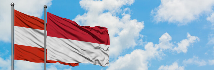 Fototapeta na wymiar Austria and Indonesia flag waving in the wind against white cloudy blue sky together. Diplomacy concept, international relations.
