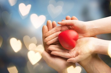 Man and woman holding red heart on background