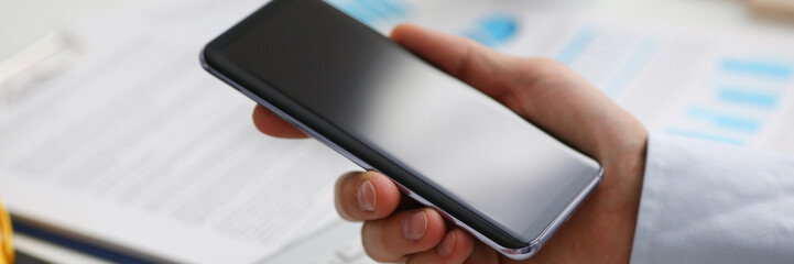A businessman holds a new smartphone in his hand