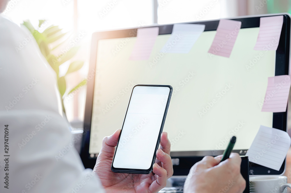 Fototapete closeup man using smartphone with blank screen while sitting at office desk, blank screen for text o