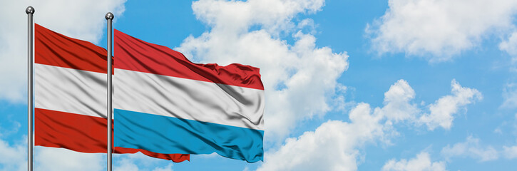 Fototapeta na wymiar Austria and Luxembourg flag waving in the wind against white cloudy blue sky together. Diplomacy concept, international relations.