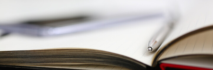 Silver pen lying on opened notebook sheet closeup