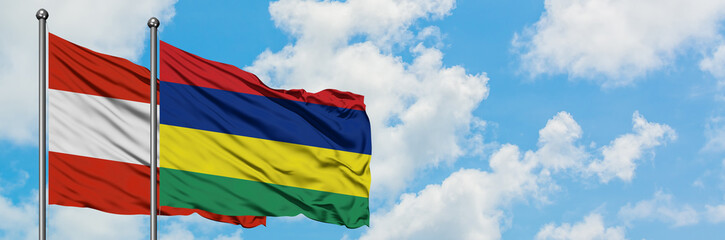 Obraz premium Austria and Mauritius flag waving in the wind against white cloudy blue sky together. Diplomacy concept, international relations.