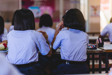 The Asian high school students in white uniform are studying in the classroom.