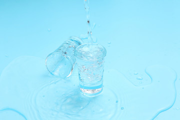 pouring vodka to shot glass on blue background with a blank space for a text, Russian vodka on color table