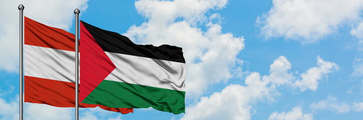 Austria and Palestine flag waving in the wind against white cloudy blue sky together. Diplomacy concept, international relations.