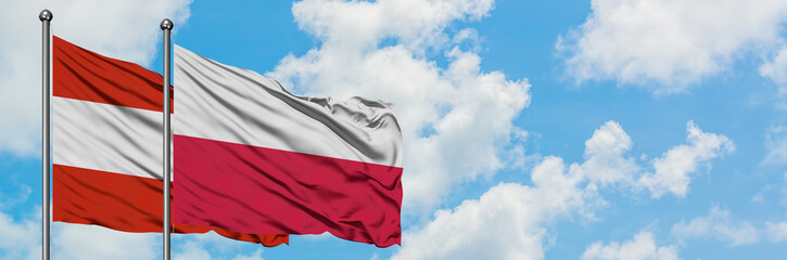 Austria and Poland flag waving in the wind against white cloudy blue sky together. Diplomacy concept, international relations.