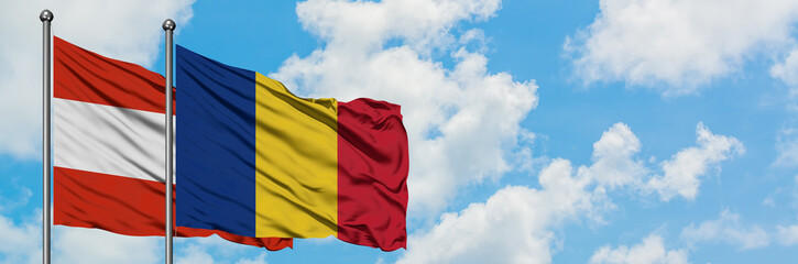 Fototapeta premium Austria and Romania flag waving in the wind against white cloudy blue sky together. Diplomacy concept, international relations.