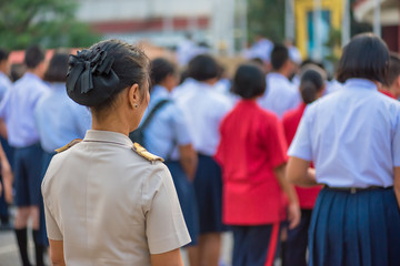 The high school teacher in Thai government teacher uniform is standing among students, Thailand, southeast Asia.