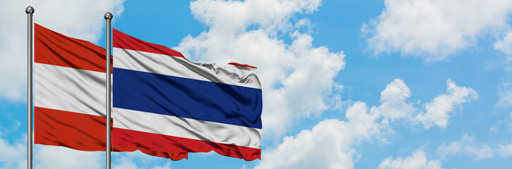Austria and Thailand flag waving in the wind against white cloudy blue sky together. Diplomacy concept, international relations.