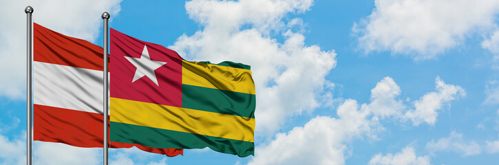 Fototapeta na wymiar Austria and Togo flag waving in the wind against white cloudy blue sky together. Diplomacy concept, international relations.
