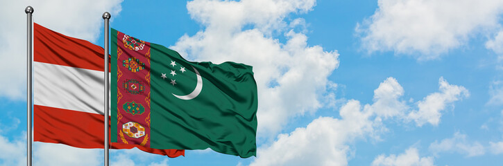 Austria and Turkmenistan flag waving in the wind against white cloudy blue sky together. Diplomacy...