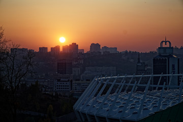 Fototapeta na wymiar Stadium construction. Aerial view of the stadium roof on the city's background. Sunset behind stadium for soccer