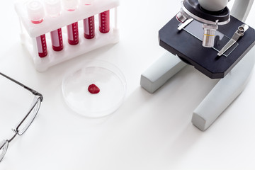 Blood testing laboratory. Samples viewing under microscope near tubes on white background top view copy space