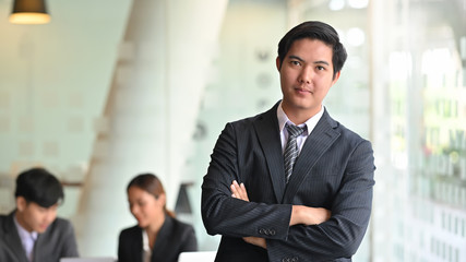Confidently businessman looking at the camera standing front of meeting room.