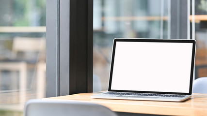 Laptop computer blank screen on wood table at cafe.