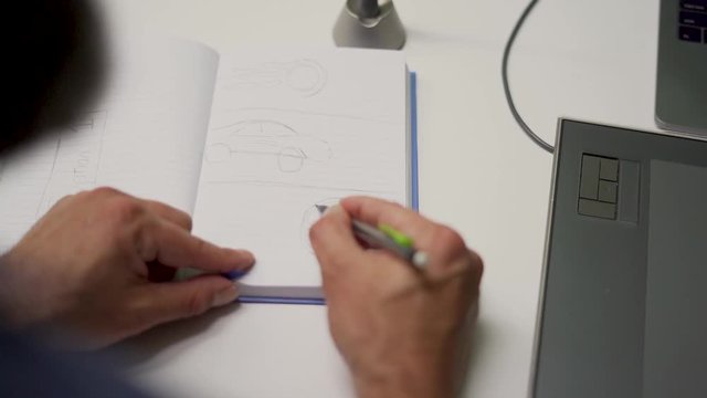 Graphic designer drawing in sketchbook over shoulder view