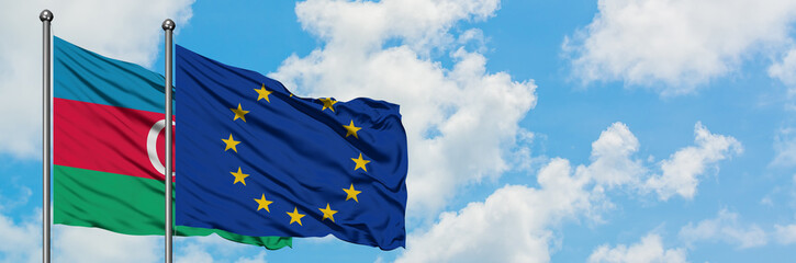 Azerbaijan and European Union flag waving in the wind against white cloudy blue sky together....