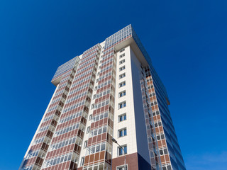 New panel white-brown residential building in the blue sky. The theme of an emerging housing market under construction