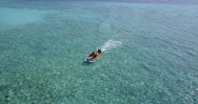 Adventurer on a small yellow boat in open waters in Hawaii, with shallow reef in aquamarine transparent water