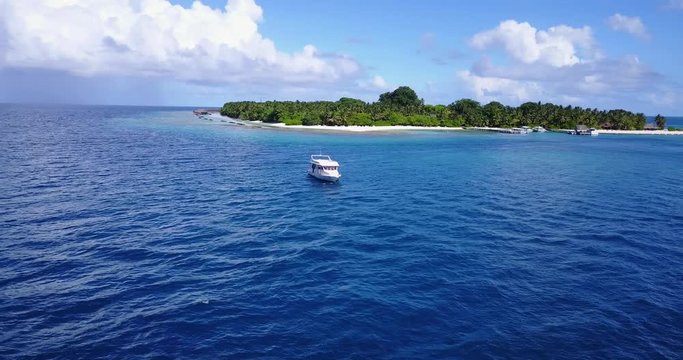 Arc shot of luxurious yacht boat off the coast of luscious island in the Bahamas